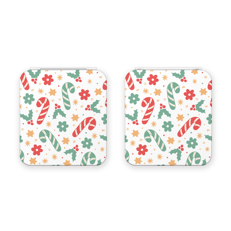 These white square coasters feature a festive pattern of red and green candy canes, red and green flowers, gold stars, and holly leaves with berries. The holiday-themed design is evenly distributed across the entire surface of each coaster, perfect for adding cheer to any cozy gamer's setup.
