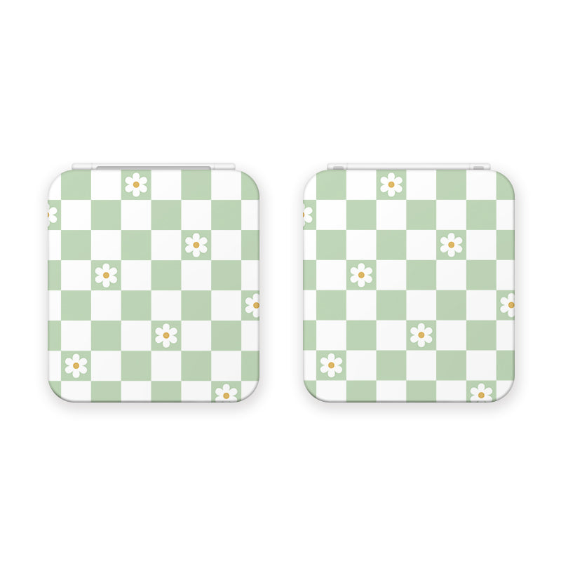 The Checkered Flowers Game Card Box for Nintendo Switch by petimint features a green and white checkerboard pattern adorned with small white daisy flowers. Reminiscent of nostalgic gaming days, this design will resonate with any gamer. The boxes are set against a plain white background.