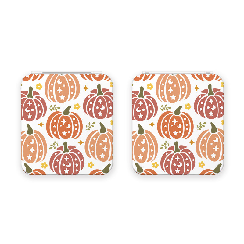 The Pumpkins Game Card Box by petimint includes two square coasters featuring a festive pumpkin pattern. Illustrated in shades of orange and red, the pumpkins are adorned with star, leaf, and floral motifs. Perfect for adding a touch of seasonal charm to your gaming setup, the coasters have a white background with small scattered yellow and orange flowers and green leaves.