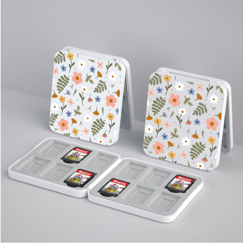 Two Spring Game Card Boxes for Nintendo Switch by petimint, crafted from white plastic and embellished with a floral pattern, hold SD cards. Each box is open, displaying multiple slots ideal for storing your Nintendo Switch game data. Two SD cards occupy some of the slots while the remaining slots are empty. One box is standing upright while the other lies flat.
