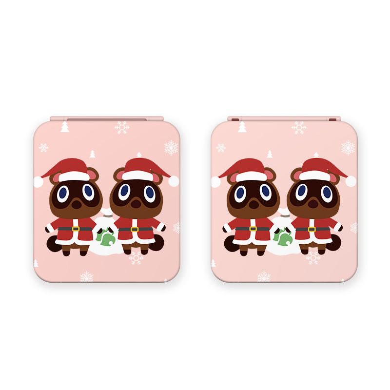 Two cartoon raccoons named Timmy and Tommy, each wearing a red Santa hat and suit, stand side by side on a pink background adorned with white snowflakes. They have big round eyes and carry green and white gift bags. This festive image from petimint is featured on the Timmy & Tommy Christmas Game Card Box for Nintendo Switch in the color pink, making it perfect for gamer-themed apparel.