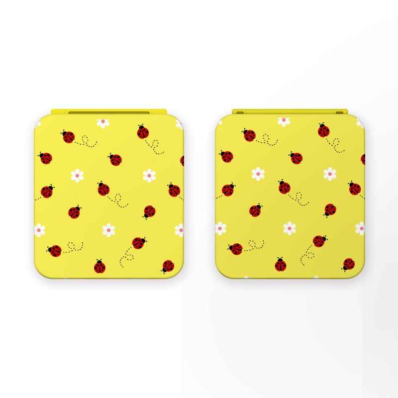 Two square yellow game card boxes with rounded corners lie side by side, each decorated with a pattern of red ladybugs, tiny black dots, and white flowers with pink centers. Perfect for cozygamer apparel, these Little Ladybug Game Card Boxes for Nintendo Switch by petimint have a plain white background.
