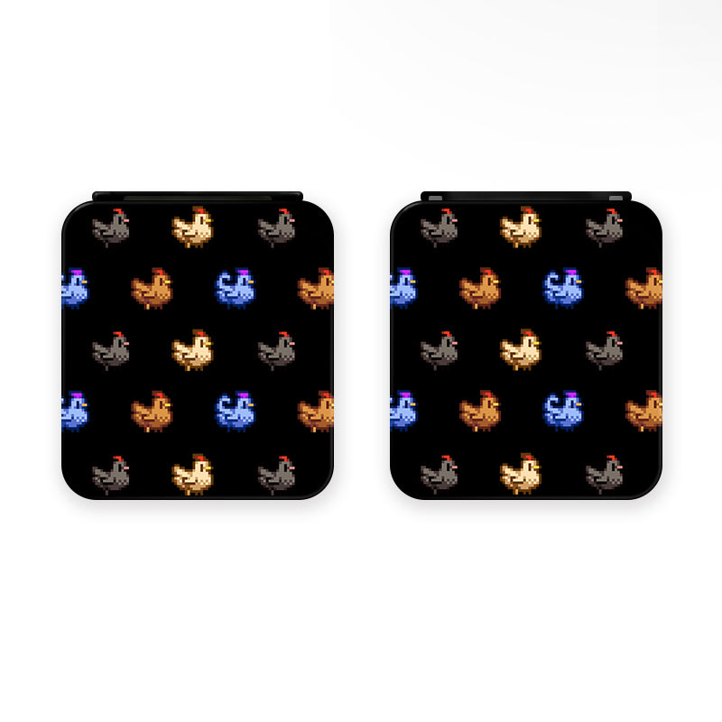 Depicted are two square objects with pixelated rooster icons in various colors, such as brown, gray, blue, yellow, and orange, set against a black background. The design has a retro video game aesthetic and would make an ideal accessory for any cozy gamer. This product is the "Chicken Stardew Valley Game Card Box for Nintendo Switch" by petimint.