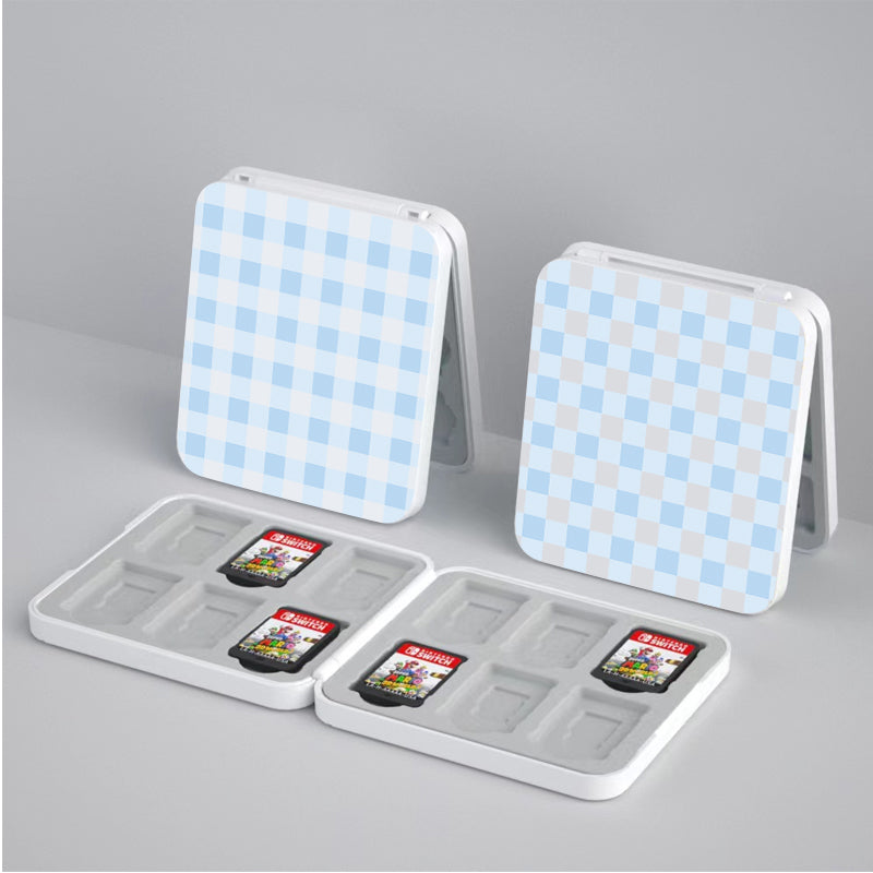 Two compact, petimint Picnic Game Card Boxes are open on a gray surface, displaying slots designed to hold small game cartridges. Each blue and white checkered case contains multiple cartridges securely placed in individual compartments—an ideal choice for the cozygamer who values both style and function.