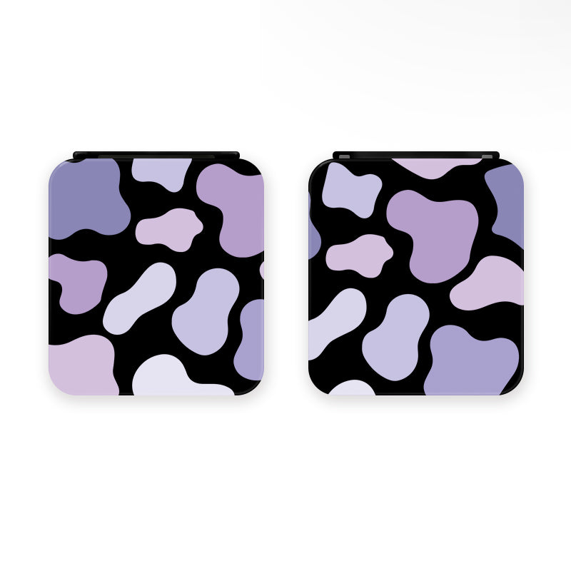 Two Lilac Cow Game Card Boxes for Nintendo Switch by petimint, each square-shaped with rounded corners and a design of irregular lavender and purple shapes on a black background. Perfect for the gamer lifestyle, these cases are displayed side by side against a plain white backdrop.