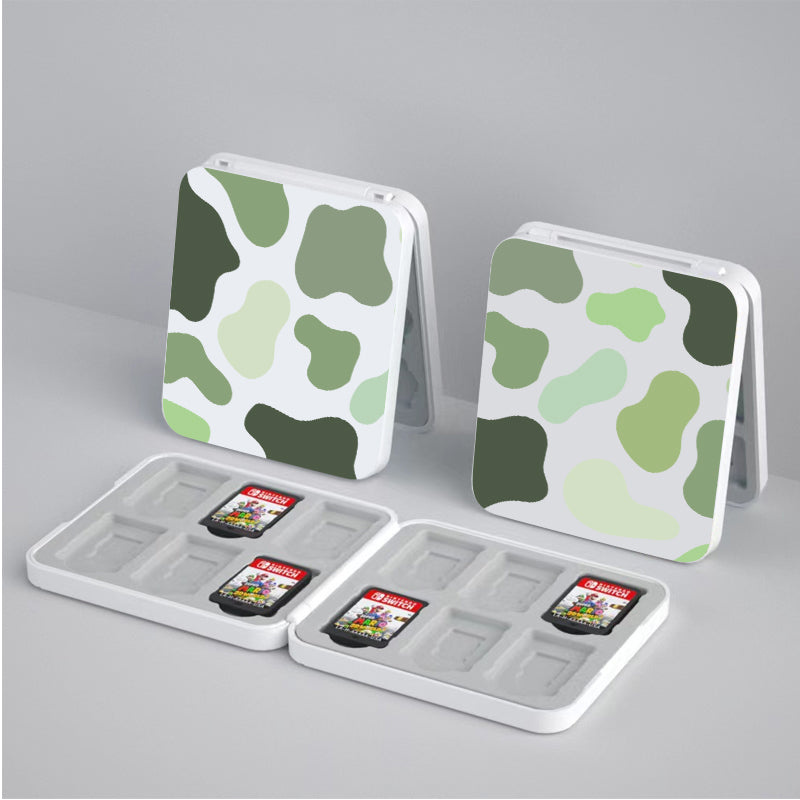 Two Matcha Cow Game Card Boxes for Nintendo Switch by petimint are on a surface, each open to reveal slots for storing video game cartridges. Each case contains two cartridges labeled "Super Mario Odyssey" and "Super Mario 3D World," along with empty slots that can hold additional games. Perfect for the cozygamer who loves stylish, organized storage!
