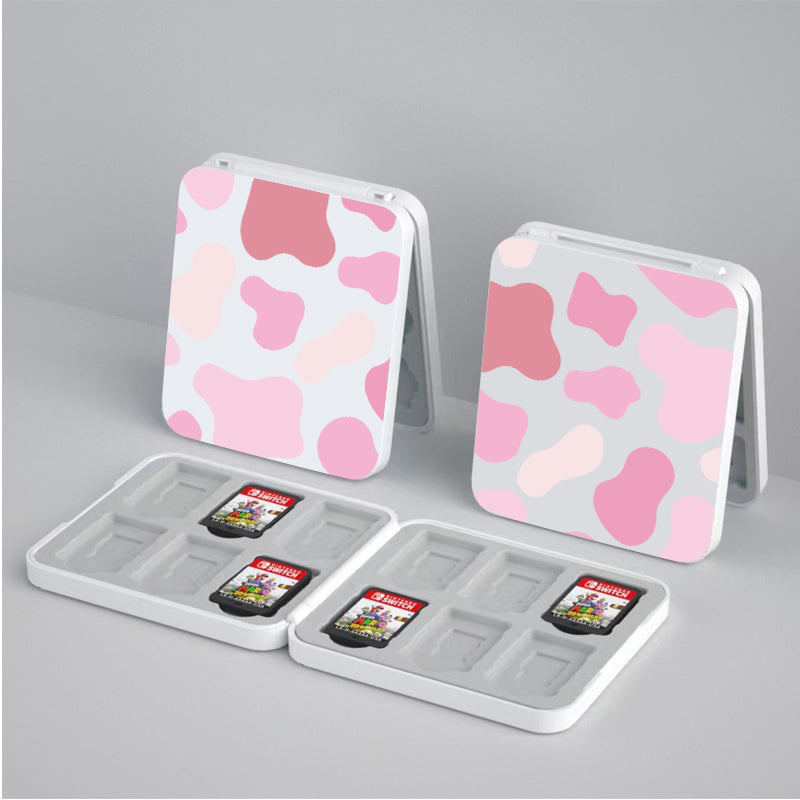Two petimint Strawberry Cow Game Card Boxes for Nintendo Switch with a pink and white camouflage pattern sit open on a gray surface. Each case holds two visible Nintendo Switch game cards featuring different cover art and has space for additional cards, making them perfect for any avid gamer.