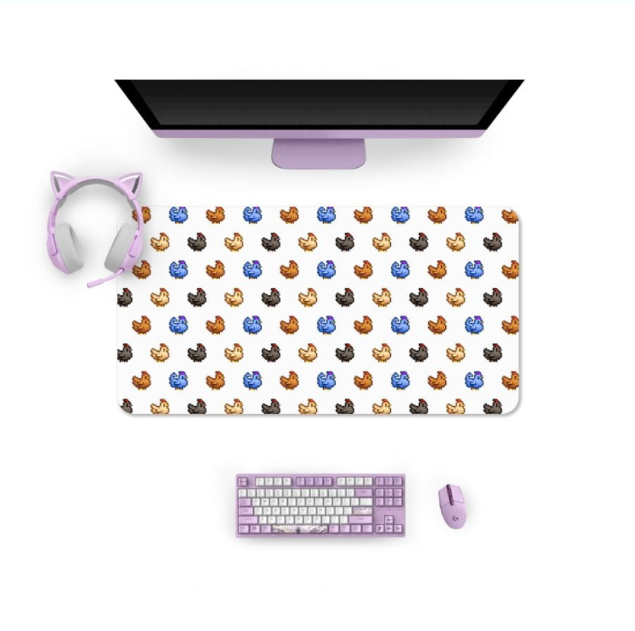 A cozy gamer's dream: a gaming setup featuring a purple keyboard, matching mouse, and cat ear headphones draped over the monitor. Beneath, the petimint Stardew Chicken Mouse Pad showcases multi-colored kittens on a white background, adding charm to your Nintendo Switch sessions.