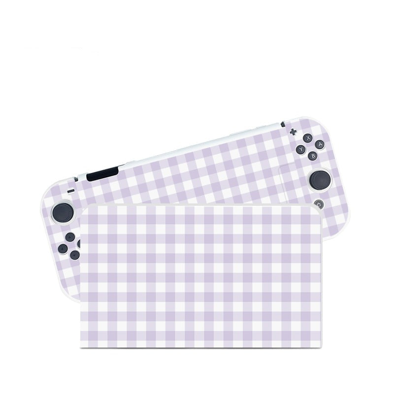 A Picnic Case for Nintendo Switch by petimint and the Nintendo Switch itself lie on a white background. The gaming console, resembling a cozygamer's delight, features a light purple and white gingham checkered pattern from the case covering its body. Buttons are visible on the right side, and part of the screen is partially covered by the same design.