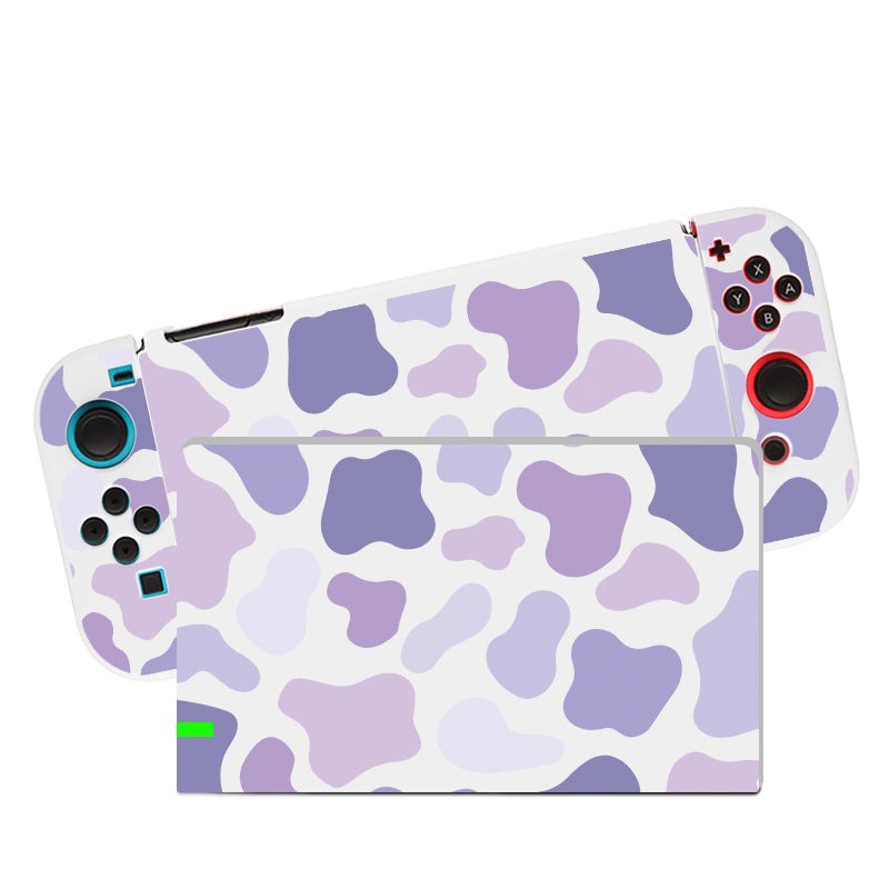 Introducing the Lilac Cow Case for Nintendo Switch by petimint, featuring a stylish white design with elegant purple camo patterns. The back of the console and attached controllers are showcased beautifully, with the left controller boasting blue and black buttons and the right one adorned with red and black buttons. It's perfect for every CozyGamer looking to elevate their Nintendo Switch setup.