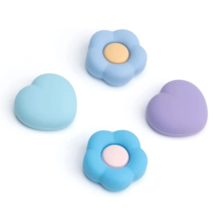 Discover the "Blue Love Flowers Thumb Grips" for Nintendo Switch by petimint—featuring four pastel-colored silicone cases: two heart-shaped in light blue and lavender, along with charming joystick caps. The set includes two flower-shaped grips, both in light blue with delicate pink and beige centers, all beautifully displayed on a white background.