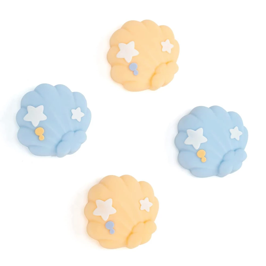 The Seashell Thumb Grips for Nintendo Switch by petimint feature a set of four pastel-colored shell-shaped caps arranged in a square. Two caps are in light blue, and two are in light orange, each decorated with small white stars and yellow dots, making them perfect for adding a touch of charm to your setup against the plain white background.