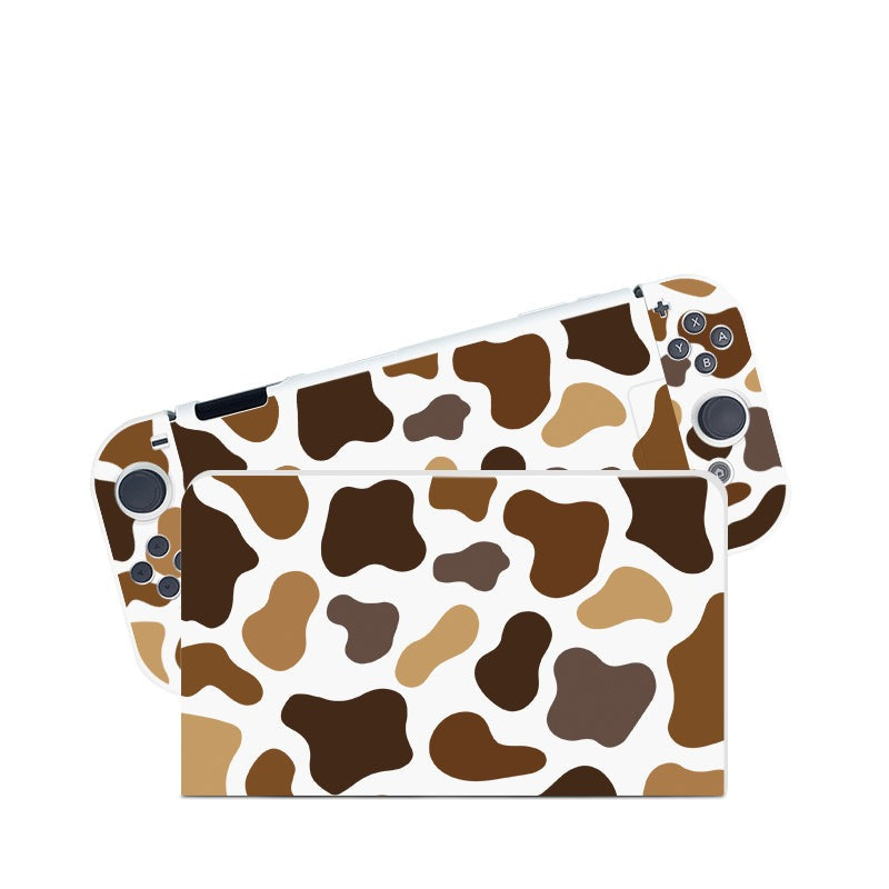 The Moka Cow Case for Nintendo Switch by petimint features a cow print skin with brown, beige, and black spots on a white background. This cozygamer design covers both the front and back of the console, including the area around the control buttons and screen.