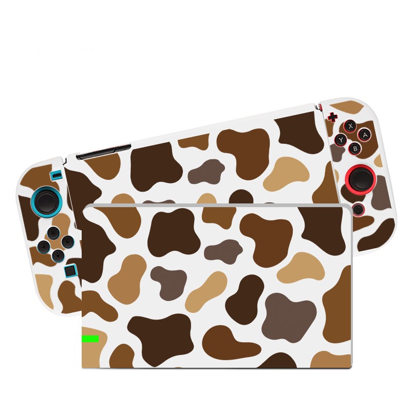 A Moka Cow Case for the Nintendo Switch, crafted by petimint, is displayed. The handheld gaming console boasts a cow print design with brown, tan, and black spots on a white background. Detachable controllers also feature this distinctive pattern and are enhanced with blue and red accents on the buttons, making it an attractive choice for any gamer.