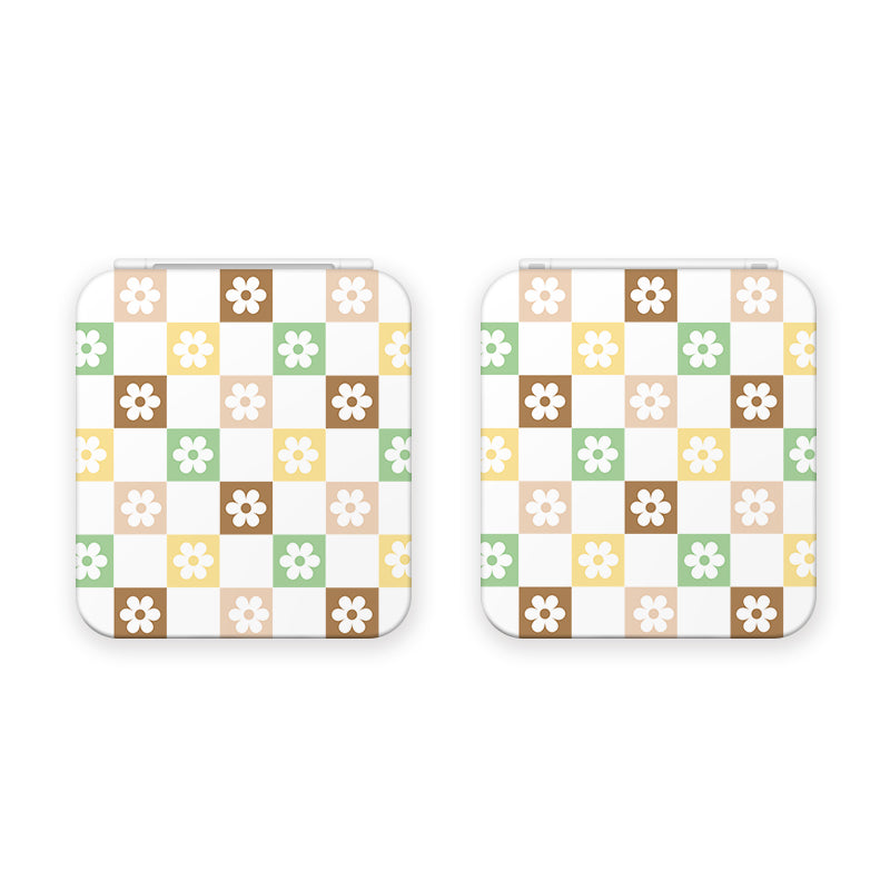 Two square objects, identified as the Checkered Seasonal Flowers Game Card Box for Nintendo Switch by petimint, display a checkered pattern with alternating pastel squares in white, brown, yellow, green, and light pink. Each square contains a small flower in a contrasting color, reminiscent of the vibrant designs often found in gamer apparel.