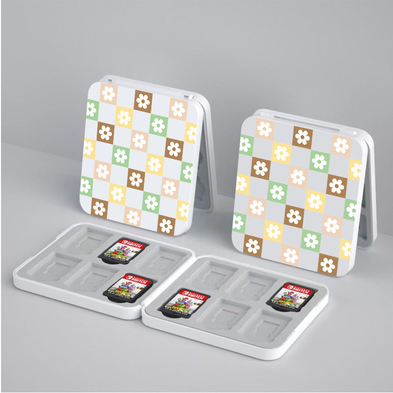 Two Checkered Seasonal Flowers Game Card Boxes for Nintendo Switch by petimint are open and displayed. One box is filled with cartridges, while the other is empty, revealing its compartments. Perfect for the cozy gamer, these holders feature various colored flowers on white, green, brown, and beige checkered squares.