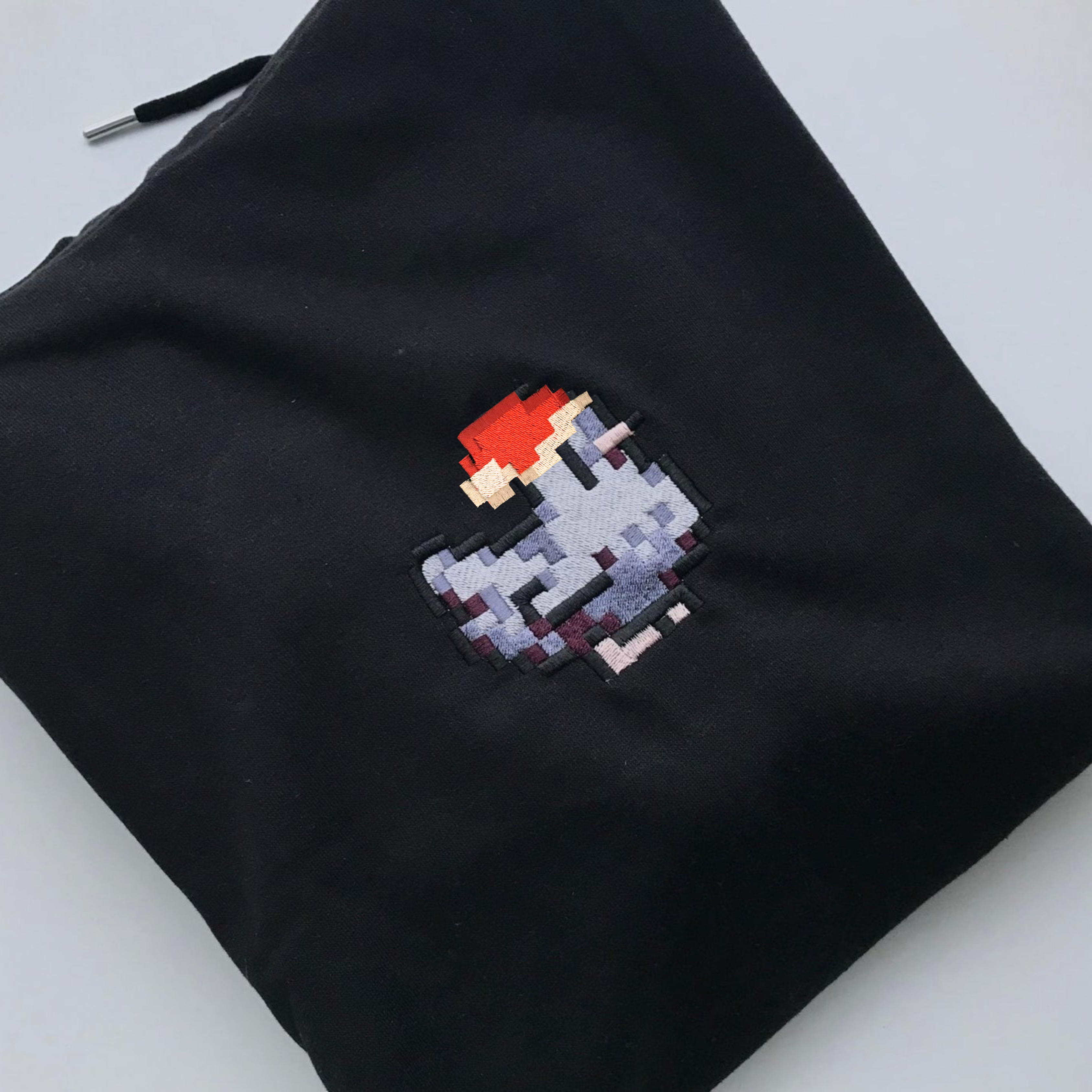 Black fabric pouch featuring pixelated embroidery of a character in a red hat and grey outfit, inspired by the Christmas Stardew Dark Chicken Hoodie from petimint, perfect for the cozygamer.