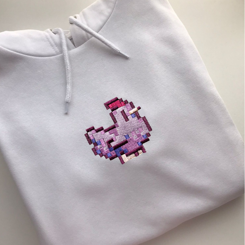 Introducing the Stardew Chicken Purple Hoodie by petimint: This stylish white hoodie features a pixel art design of a purple bird on the front. The bird, facing to the left, showcases pixelated shades of purple and pink that evoke a retro, video game-like aesthetic—perfect for any cozygamer. The hoodie is displayed laid flat on a plain surface.