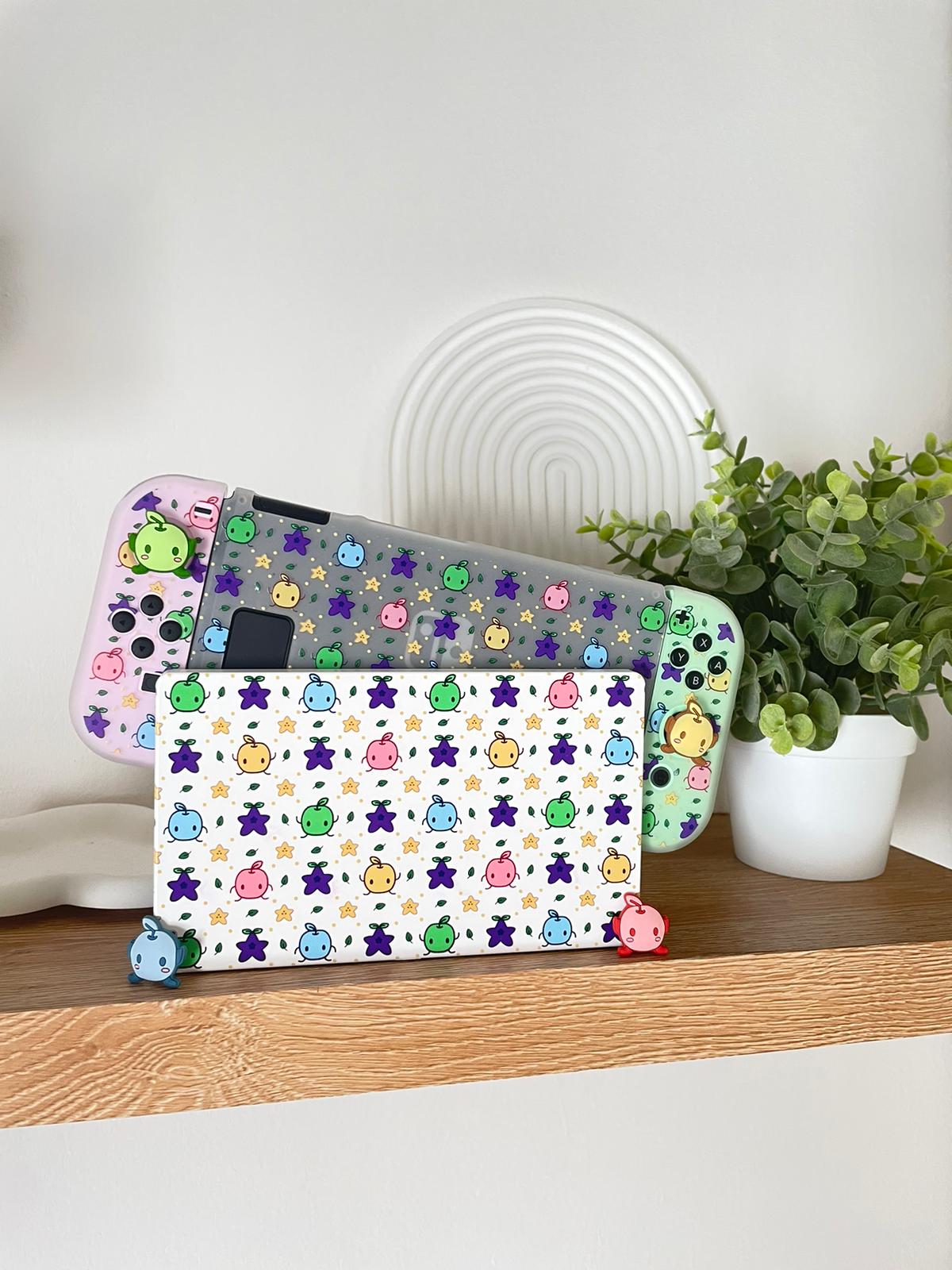 A Nintendo Switch, adorned with colorful animal stickers, sits on a wooden shelf next to a small potted plant. The gaming console has a customized dock featuring a white background with various colorful animal designs.